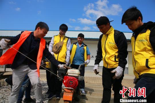 中国教师（右一）指导留学生使用轨枕螺丝机动扳手。　朱柳融 摄
